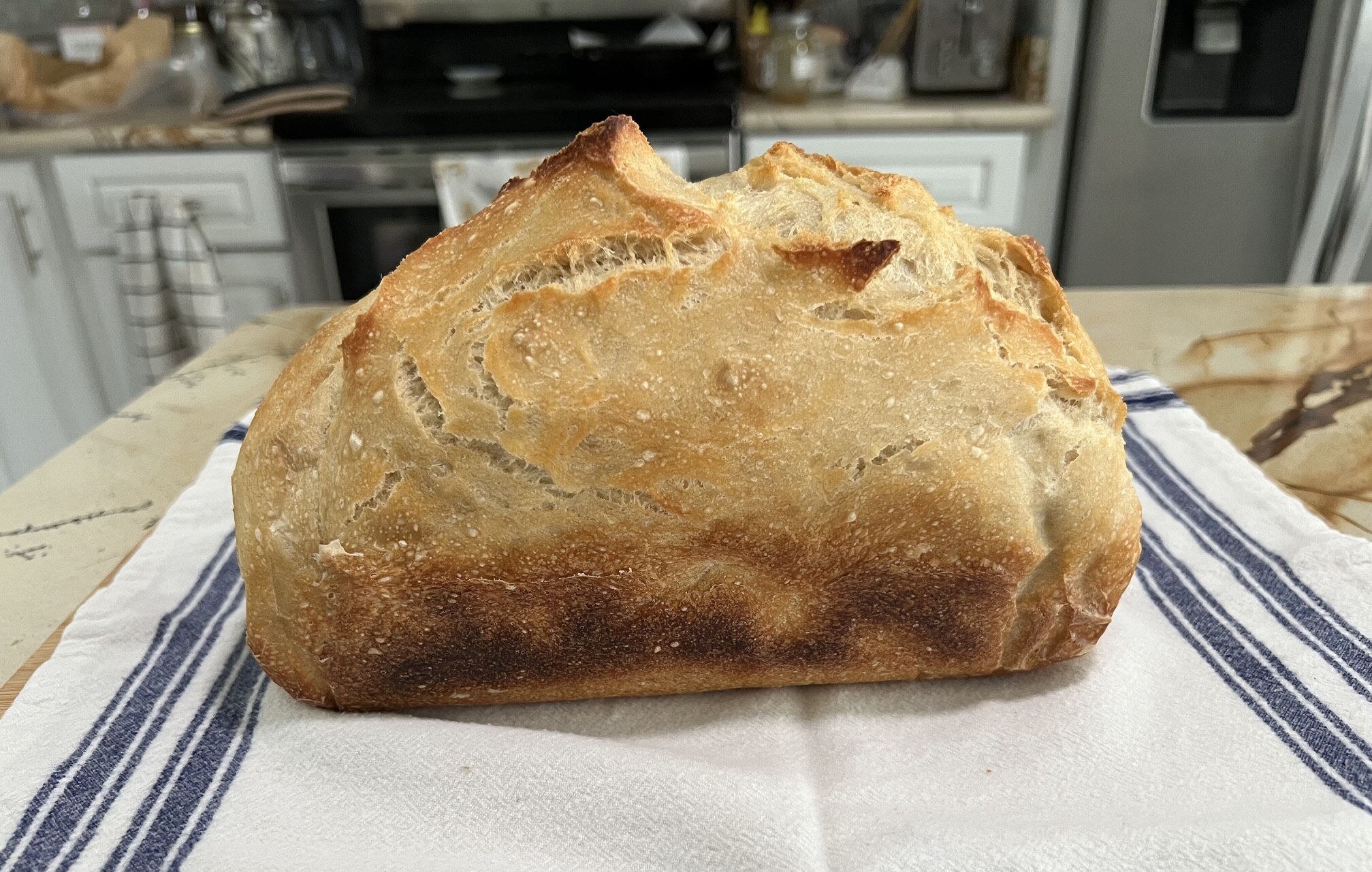 Barb’s finished organic sourdough loaf with a deeply golden crust on a striped kitchen towel